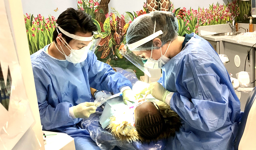 Two dentists caring for a patient in the pediatric dentistry clinic